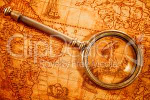 Vintage magnifying glass lies on an ancient world map