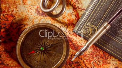 Vintage book, compass, telescope and a pocket watch lying on ancient world map in 1565.