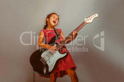 Girl European appearance ten years playing guitar on a blue  bac