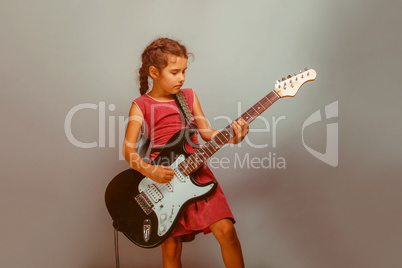 Girl European appearance ten years playing guitar on a blue back