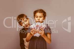 girl holding money bills in the hands of the boy opened his mout