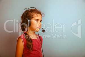 Teen girl child in headphones with a microphone on a blue backgr