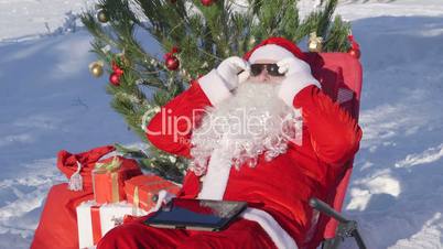 Santa Claus near Christmas tree in snow covered winter forestt
