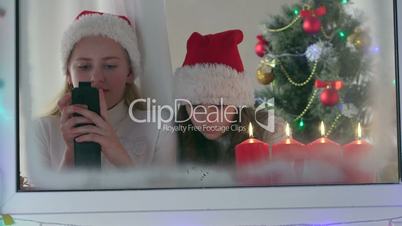 Little girls with gifted new smart phones at home near Christmas tree