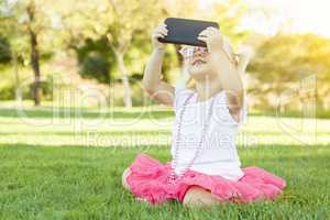 Little Girl In Grass Taking Selfie With Cell Phone