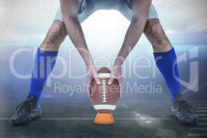 Composite image of american football player placing ball between