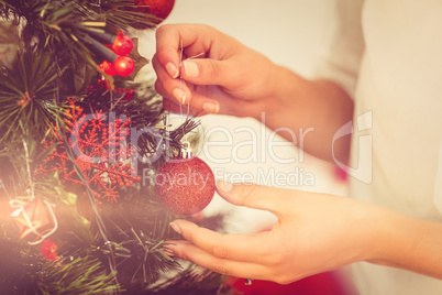 Woman hanging christmas decorations on tree