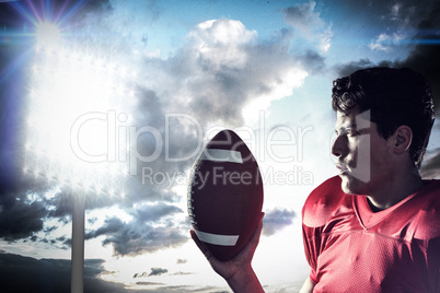 Composite image of confident sportsman holding american football