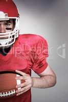 Composite image of american football player holding a ball