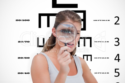 Composite image of young woman looking through a magnifying glas