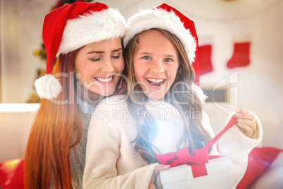 Festive mother and daughter on the couch with gift