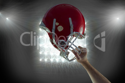 Composite image of american football player holding up his helme