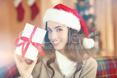 Festive brunette showing gift at christmas