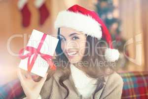 Festive brunette showing gift at christmas