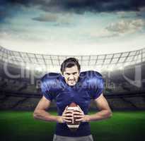 Composite image of aggressive american football player holding b