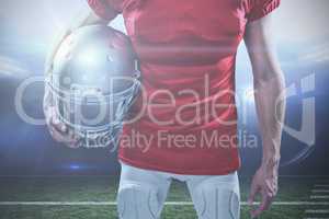 Composite image of american football player holding helmet aside
