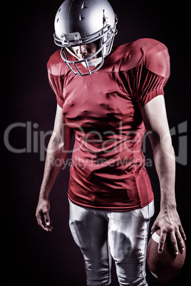 Composite image of american football player looking down while s