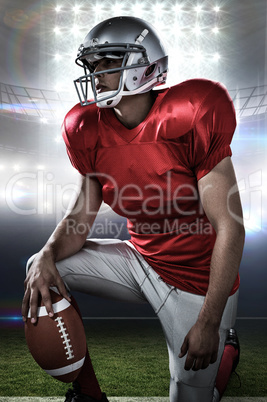 Composite image of sportsman holding american football while kne