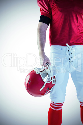 Front view of American football player holding his helmet