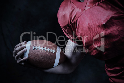 Composite image of cropped american football player holding ball