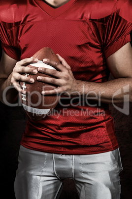 Composite image of mid section of american football player holdi