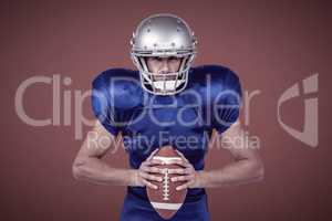 Composite image of confident american football player holding ball