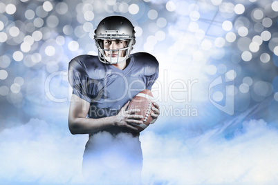 Composite image of confident american football player holding ba