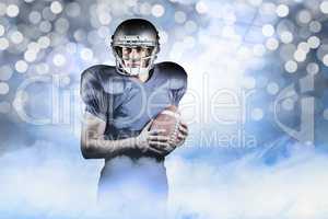 Composite image of confident american football player holding ba