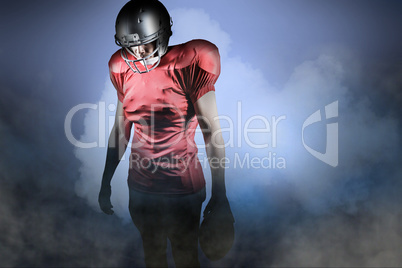 Composite image of american football player looking down while s