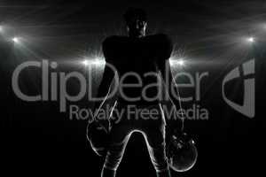 Composite image of silhouette american football player holding b