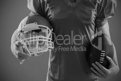 Composite image of american football player holding a helmet and