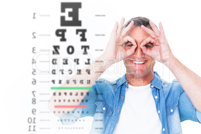 Composite image of smiling man with fingers around his eyes