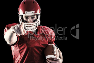 Composite image of portrait of american football player holding football and pointing to camera