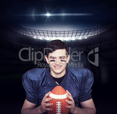 Composite image of smiling american football player holding a ba