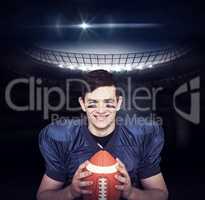 Composite image of smiling american football player holding a ba