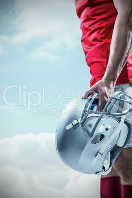 Composite image of american football player holding helmet