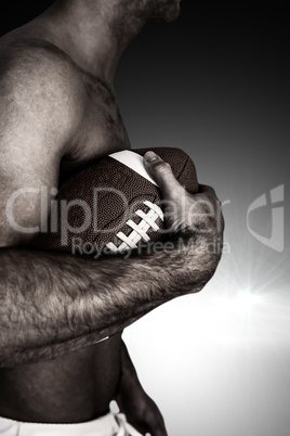 Composite image of side view of shirtless rugby player holding b