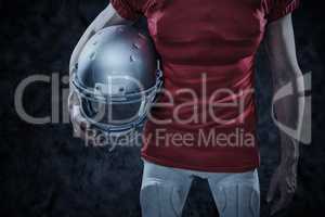 Composite image of american football player holding helmet aside