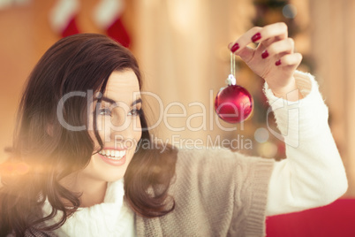 Smiling brunette holding a bauble at christmas