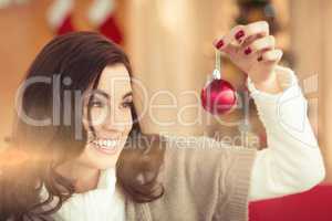 Smiling brunette holding a bauble at christmas