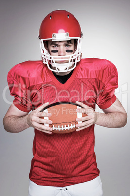 Composite image of american football player holding a ball