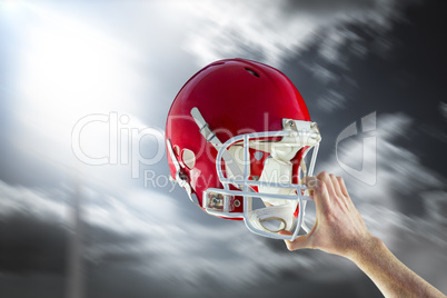 Composite image of american football player holding up his helme