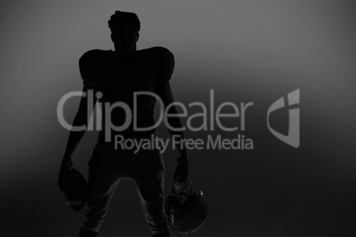Silhouette American football player holding ball and helmet