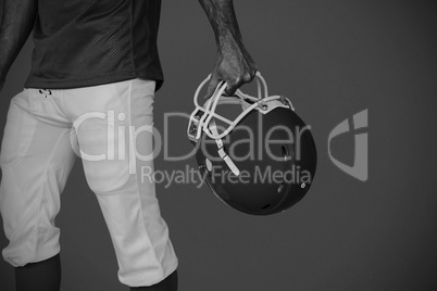 Composite image of midsection of player holding rugby helmet