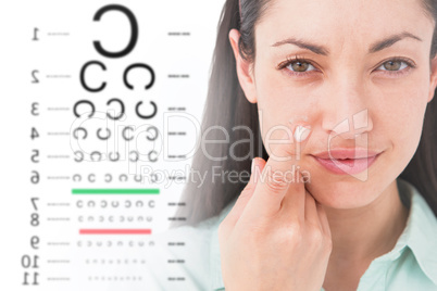 Composite image of brunette holding contact lens and smiling at