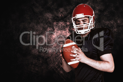 Composite image of serious american football player holding a ba