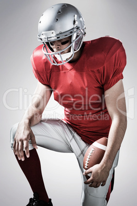 Composite image of american football player with hand on knee