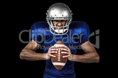 Composite image of portrait of aggressive american football player holding ball