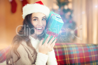 Festive brunette holding gift at christmas