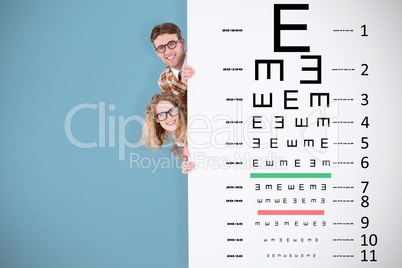Composite image of geeky hipster holding poster and smiling at c